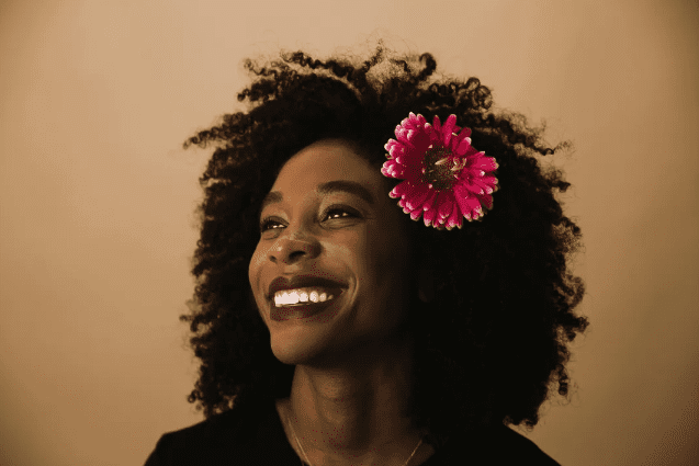 Woman with curly hair and a flower behind her ear.