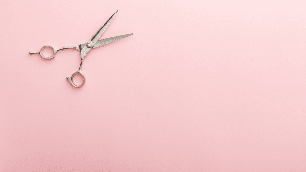 Silver scissors on pink background.