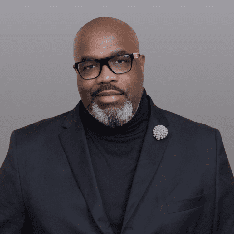 Man in suit with glasses and beard.