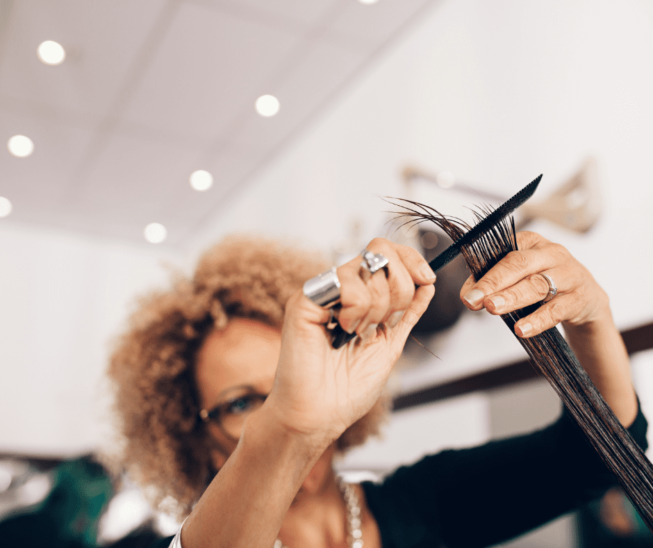 Woman cutting long dark hair with comb.