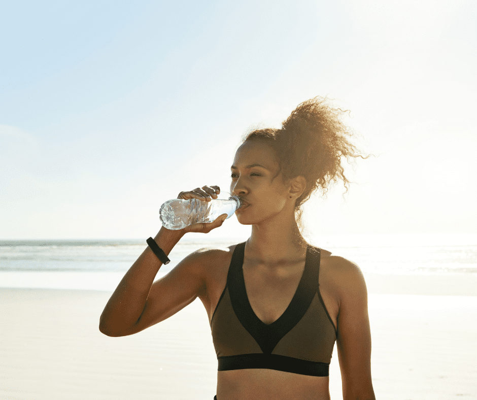 Woman drinks water on the beach.